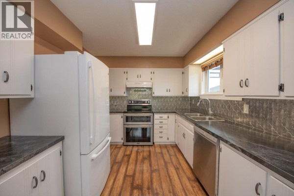 Kitchen with white cabinets, dark countertops, stainless steel appliances, and wood floors. - 2855 Burns Avenue, Armstrong