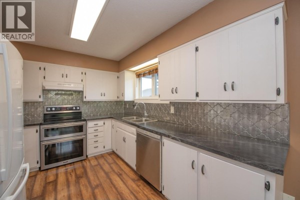 Kitchen with white cabinets, dark countertops, stainless steel appliances, and patterned backsplash. - 2855 Burns Avenue, Armstrong