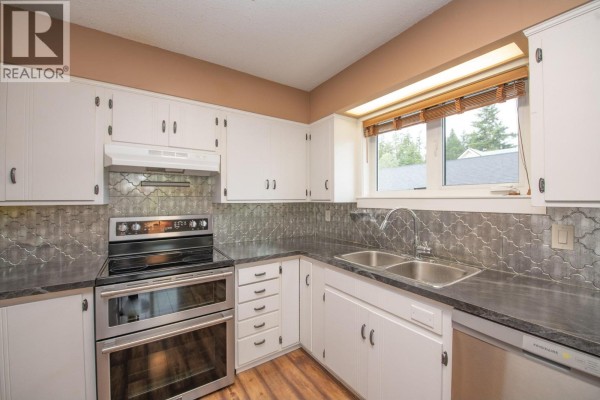 Kitchen with white cabinets, dark countertops, stainless steel appliances, and a double sink under a window. - 2855 Burns Avenue, Armstrong