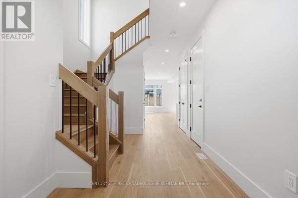 Close-up of the house entrance with double black doors, brick facade, and a contemporary porch light. - 2859 Buroak Drive, London North