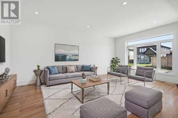 Bright white foyer with natural wood floors, a modern staircase with black spindles, and double front doors. - 2859 Buroak Drive, London North
