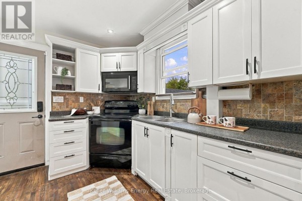Kitchen with white cabinets, stainless steel sink, and tile backsplash. - 286 Gliddon Avenue, Oshawa