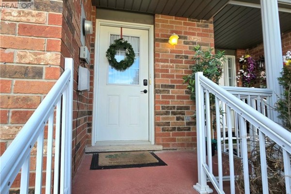 Entrance to the townhouse with a front door, staircase, and blooming pink flowers and green bushes. - 286 Sophia Crescent, Kitchener
