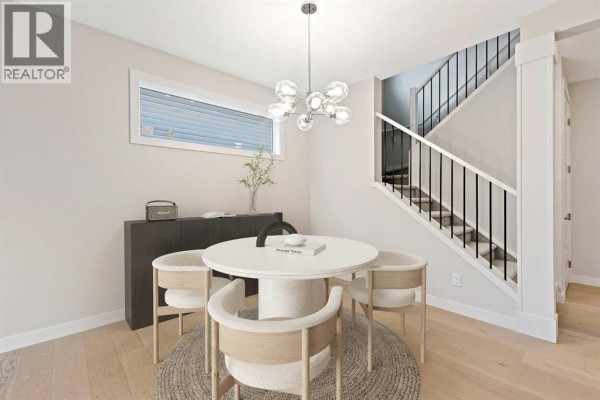 Dining area with round table, chairs, decorative chandelier, and view of staircase. - 286 Waterford Road, Chestermere