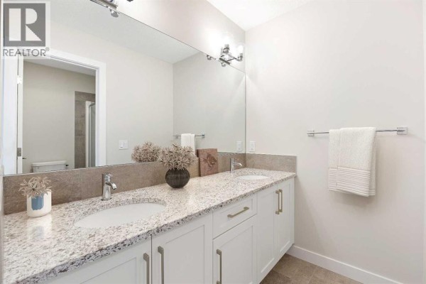 En-suite bathroom with double vanity, granite countertops, white cabinets, and tiled floor. - 286 Waterford Road, Chestermere