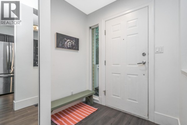 Interior entryway with a white door, bench, art, and a glimpse of a stainless steel refrigerator. - 2866 Sotao Avenue, Vancouver