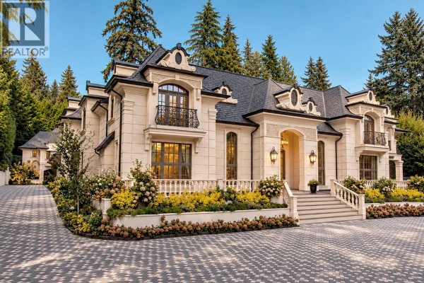 Side view of a stone mansion with a paved driveway and lush green landscaping. - 2867 Marine Drive, West Vancouver