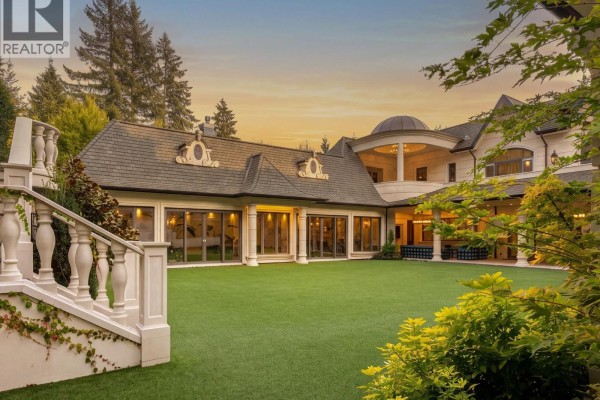 Backyard lawn and patio area of a large residence with floor-to-ceiling windows. - 2867 Marine Drive, West Vancouver