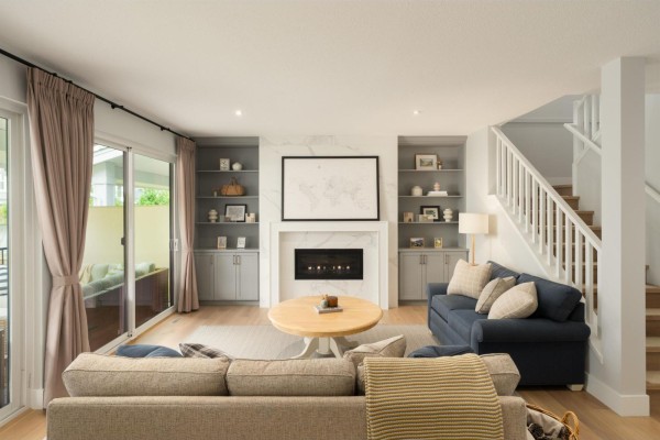 Living room with a fireplace, built-in shelving, a blue sofa, and a large sliding glass door. - 2878 203 Street, Langley