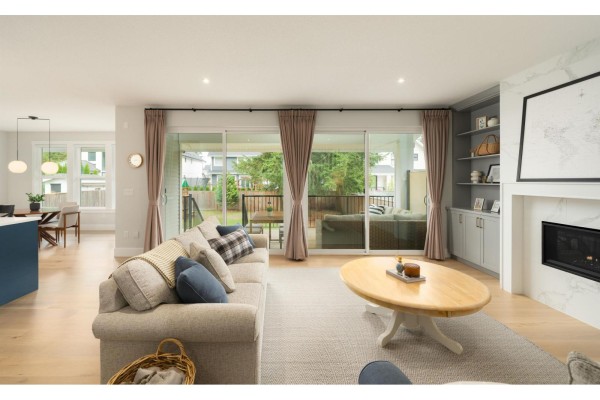 Living room with sliding glass doors opening to a patio, a fireplace, and a view of the kitchen and dining area. - 2878 203 Street, Langley