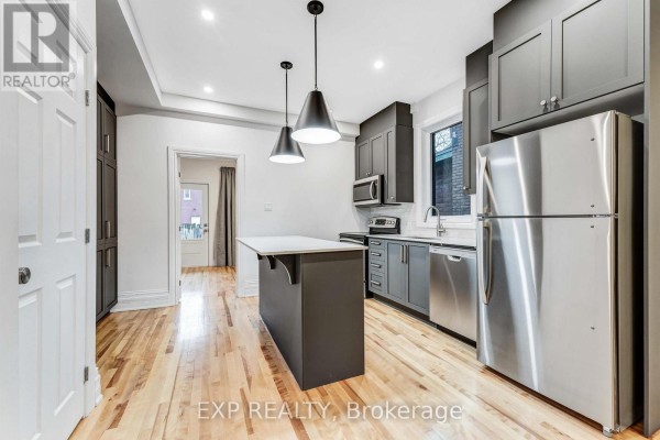 Open concept kitchen with dark grey cabinets, stainless steel appliances, and hardwood flooring. - 288 Arlington Avenue, Ottawa