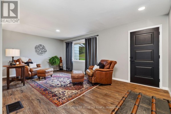 Living room with grey walls, leather chairs and ottomans, a Persian rug, and a black door. - 288 Musquash Road, Gravenhurst)