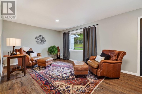 Living room with leather seating, a large Persian rug, dark curtains, and a view through the window. - 288 Musquash Road, Gravenhurst)