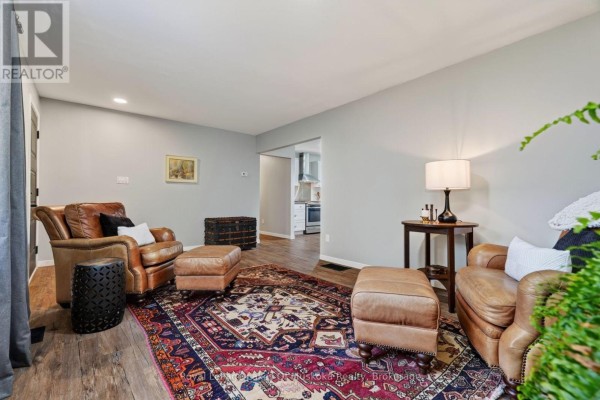 Living room with leather chairs, a Persian rug, dark wood flooring, and an open doorway to the kitchen. - 288 Musquash Road, Gravenhurst)