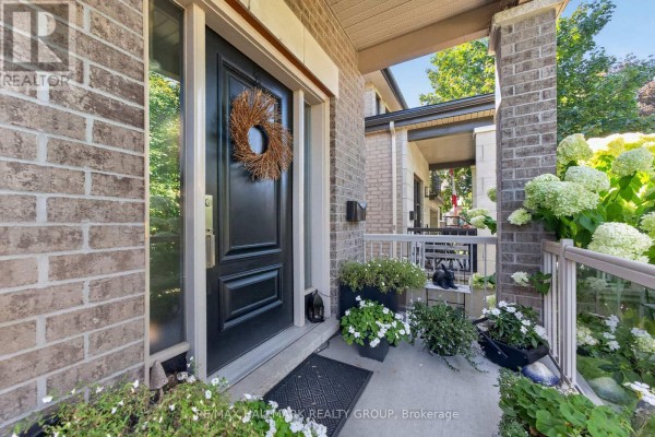 Close-up of the dark front door with a wreath, surrounded by brick and plants on the porch. - 288 Selby Avenue, Ottawa
