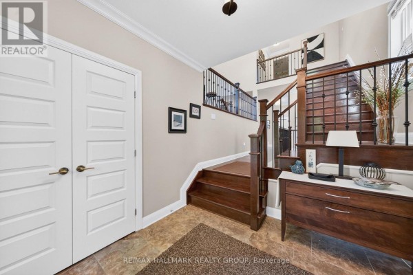 Foyer area with white double doors, a dark wood staircase, and a wooden console table. - 288 Selby Avenue, Ottawa