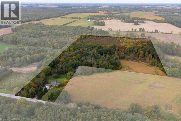 Aerial overview of a rural property showing the house, driveway, attached garage, surrounded by trees and fields. - 288 Thirteenth Concession Road, Scotland