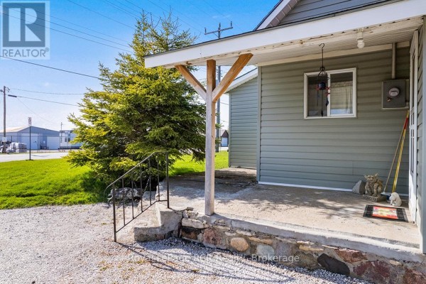 View of the concrete porch with a wooden support beam and a small evergreen tree. - 2882 6 Highway, Northern Bruce Peninsula