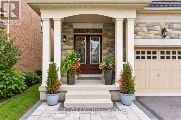 Covered front entrance with stone pillars, glass double doors, and potted plants. - 289 Chatfield Drive, Vaughan