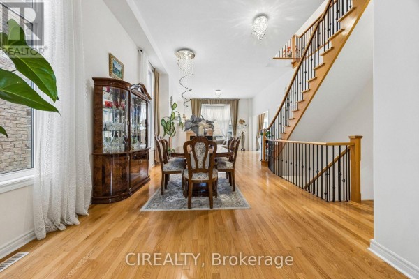 Open-concept dining room with a wooden table, chairs, china cabinet, and hardwood floors. - 289 Chatfield Drive, Vaughan