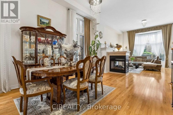 Dining area with a large table, fireplace, and living room furniture visible. - 289 Chatfield Drive, Vaughan