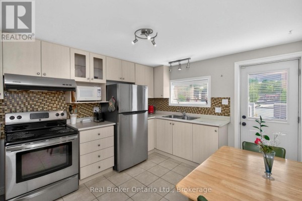 Kitchen with stainless steel appliances, wood cabinets, and a table by the door. - 289 King Street, Midland