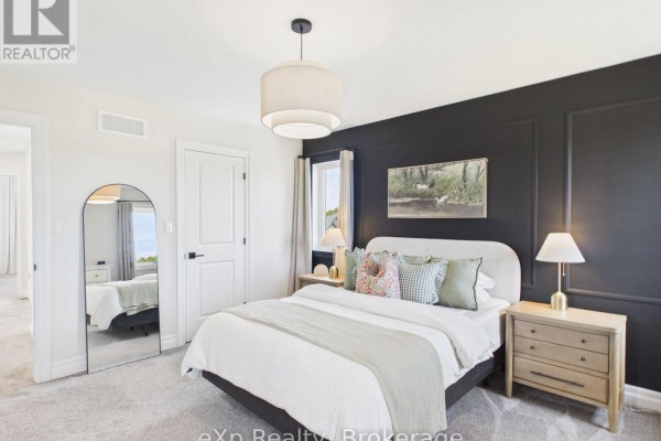 Bedroom with a queen bed, white bedding, a black accent wall, and a large arched mirror. - 289 Mary Rose Avenue, Saugeen Shores
