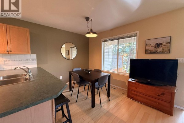 Bedroom with a queen bed, white nightstands, and two closet doors. - 28a Wolf Crescent, Invermere