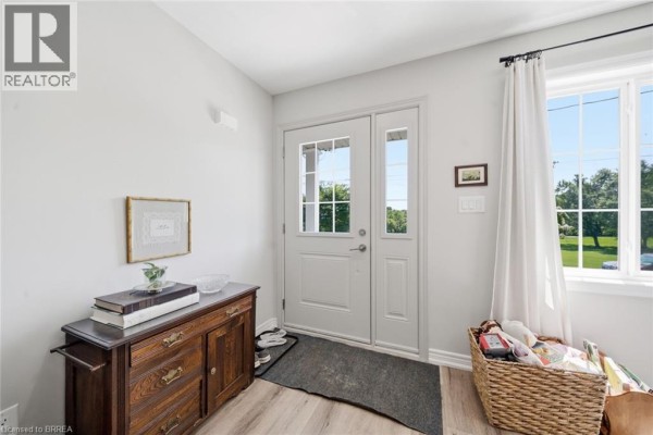 Interior foyer with double doors, wood cabinet, rug, and basket of items. - 28b Grandview Street, Brantford