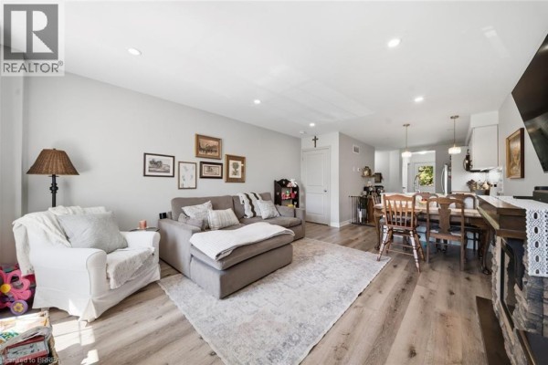 Living and dining area with a sectional sofa, chairs, dining table, and fireplace. - 28b Grandview Street, Brantford