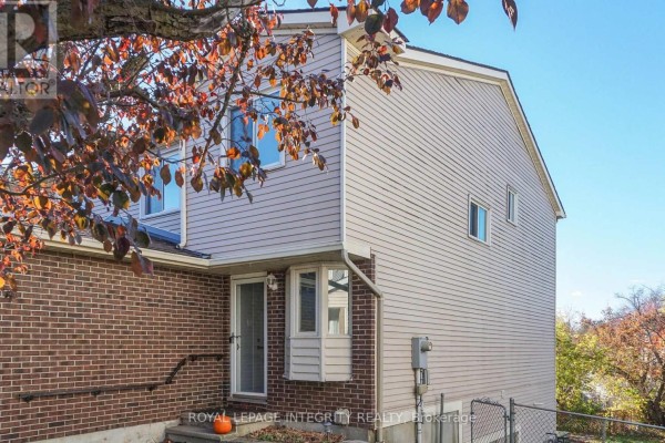 Side exterior view of a townhouse showing brick and vinyl siding with a fenced backyard. - 29 - 1080 Ormes Place, Ottawa