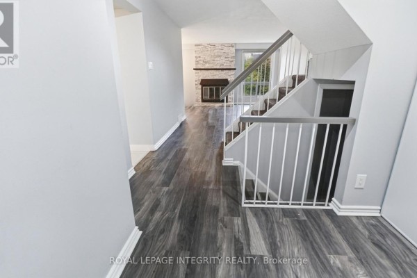 Interior hallway view with gray wood-look flooring, white baseboards, and a staircase with gray railings. - 29 - 1080 Ormes Place, Ottawa