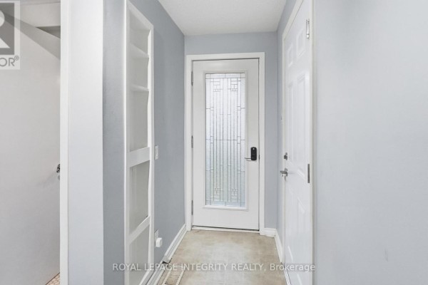 Interior hallway with a decorative glass door, two white doors, and a tall white built-in shelf. - 29 - 1080 Ormes Place, Ottawa