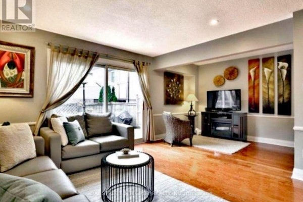 Living room featuring a sectional sofa, entertainment center with TV, and sliding glass doors. - 29 - 1580 Lancaster Drive, Oakville