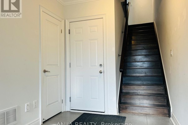 Interior entrance hallway with a white front door, closet door, and dark wood stairs. - 29 - 1812 Burnhamthorpe Road E, Mississauga