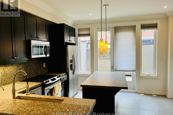 Kitchen with dark cabinets, stainless steel appliances, granite countertops, and island. - 29 - 1812 Burnhamthorpe Road E, Mississauga