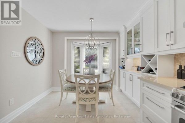 Breakfast nook with a round table and chairs next to a bay window and white cabinetry. - 29 - 3265 South Millway, Mississauga