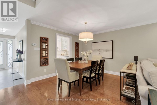 Dining room with a large wooden table, chairs, fireplace, and a view of the entrance and kitchen. - 29 - 3265 South Millway, Mississauga