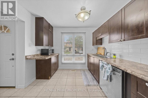 Kitchen with dark wood cabinets, stainless steel appliances, and a double sink. - 29 - 6252 Castille Court, Ottawa