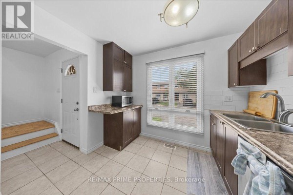 Kitchen area with dark cabinets, stainless steel appliances, and a window overlooking the exterior. - 29 - 6252 Castille Court, Ottawa