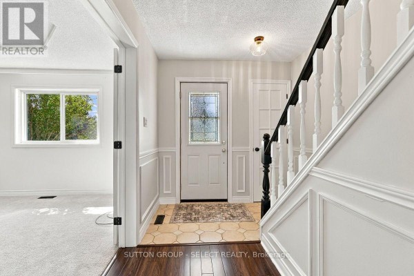 Interior view of a townhouse foyer with a white door, glass insert, and wainscoting. - 29 - 669 Osgoode Drive, London South