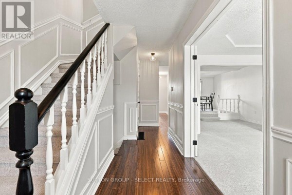 Interior view of a townhouse hallway with a staircase, wood floor, and wainscoting. - 29 - 669 Osgoode Drive, London South