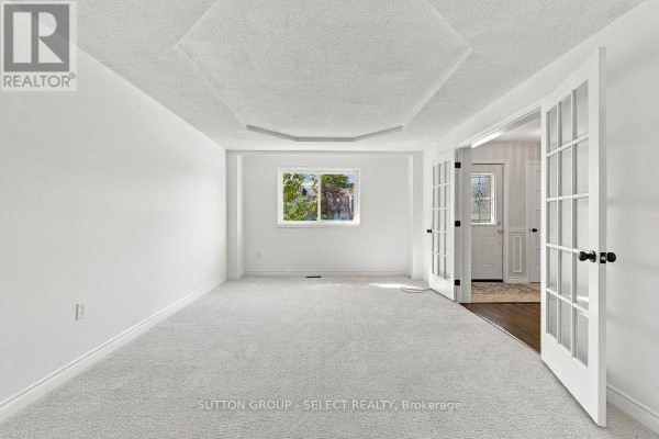 Interior view of a spacious living room with white walls, carpet, and French doors. - 29 - 669 Osgoode Drive, London South