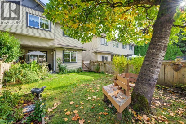 Living room with a navy blue sofa, wooden coffee table, fireplace with green tiles, and a door to the balcony. - 29 11229 232 Street, Maple Ridge