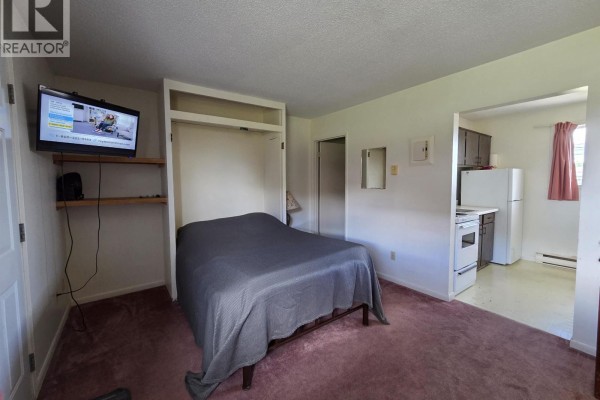 Bedroom with murphy bed, and a small kitchen area visible to the right. - 29 50 Hagan Street, Granisle