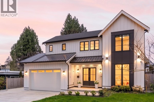 Exterior of a modern white house with black trim and metal roof at dusk. - 29 50 Street, Delta