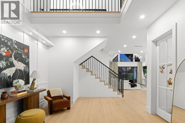 Spacious foyer with a staircase, console table, artwork, and a view into the living area. - 29 50 Street, Delta