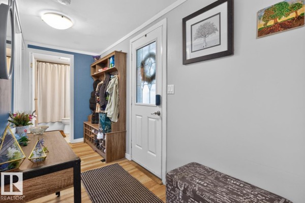 Interior entryway with light grey walls, a white door, and a wooden shoe rack. - 29 5220 44 Av, Calmar