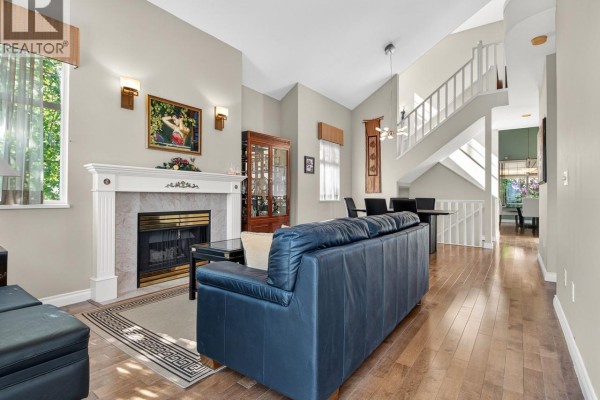 Living room with fireplace, vaulted ceiling, dining area, and staircase. - 29 5221 Oakmount Crescent, Burnaby