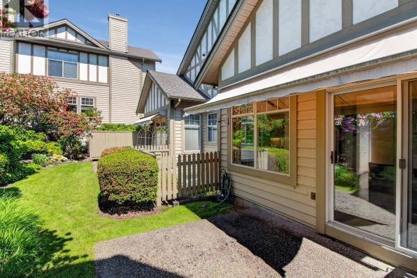Backyard patio with grass, landscaping, and townhouse exterior. - 29 5221 Oakmount Crescent, Burnaby
